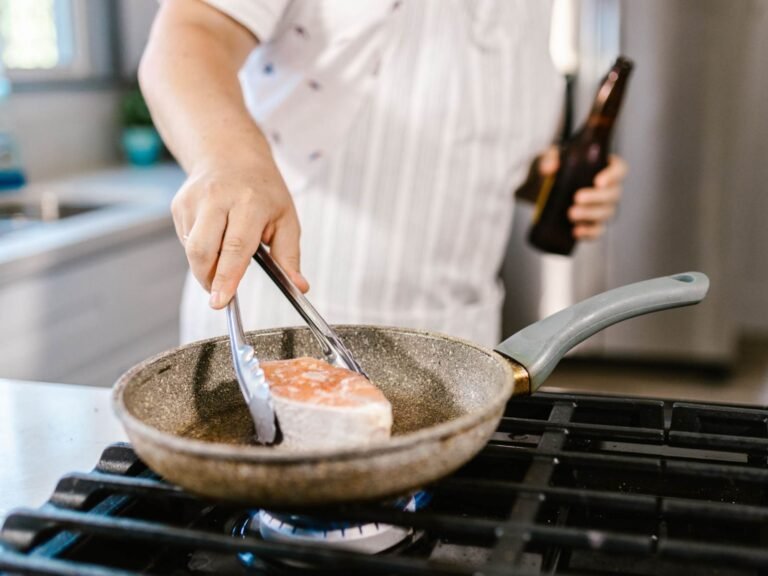 cuoco cuoce salmone in una padella