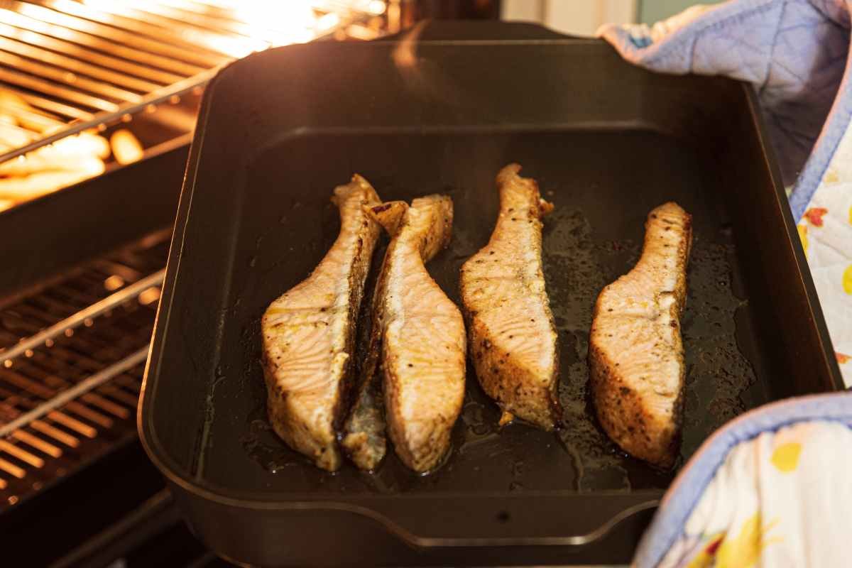 persona sforna tranci di pesce in una griglia