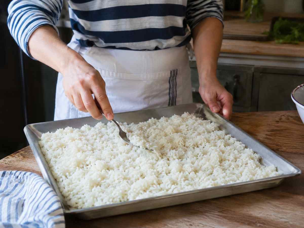 donna stende riso su una leccarda