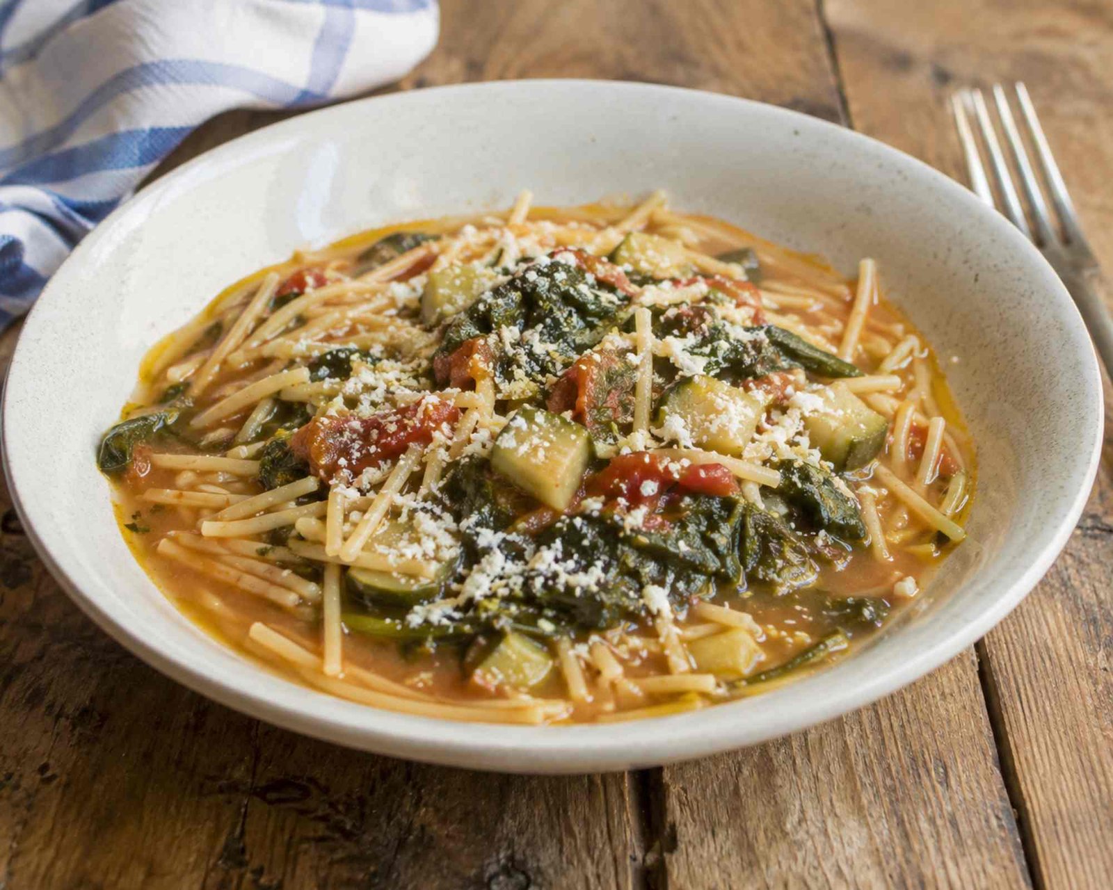 piatto di spaghetti rotti con zucchine, foglie di zucchine e sugo di pomodoro